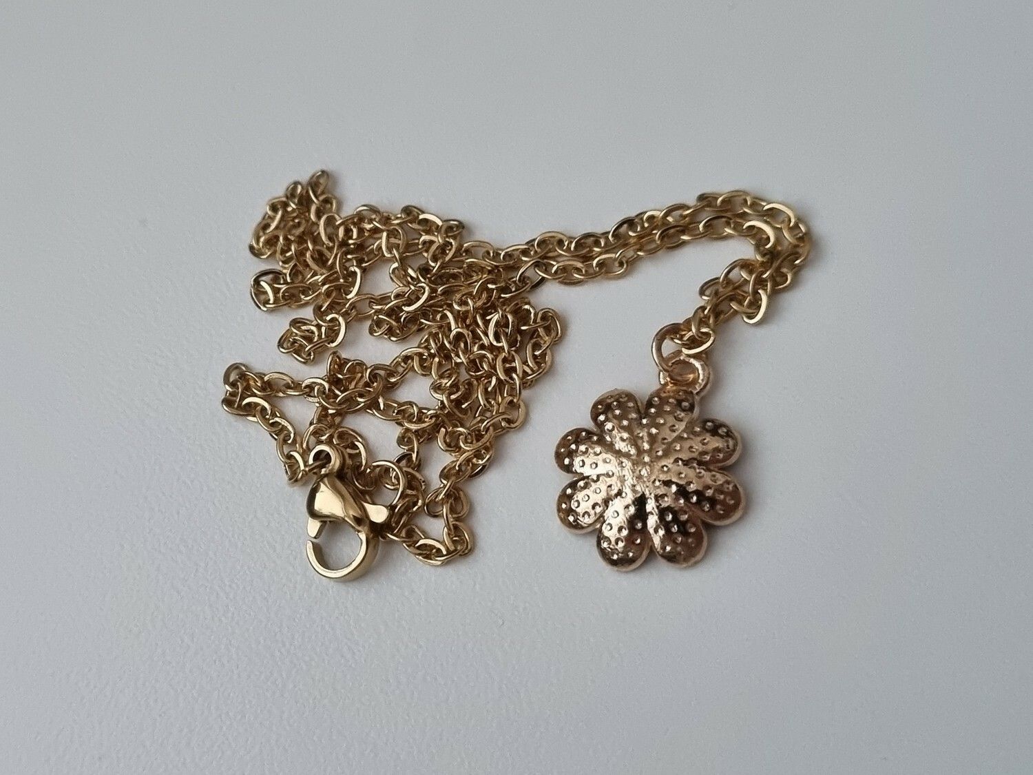 Guldfärgat halsband med en blomma
