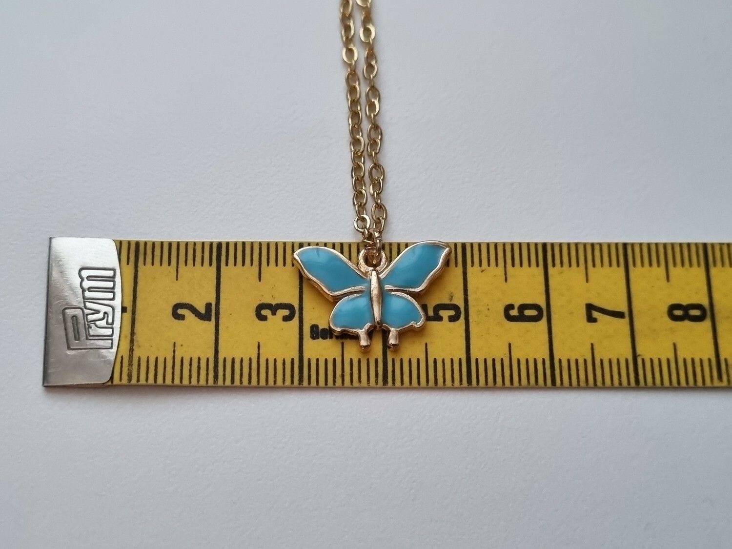 Guldfärgat halsband med en blå fjäril