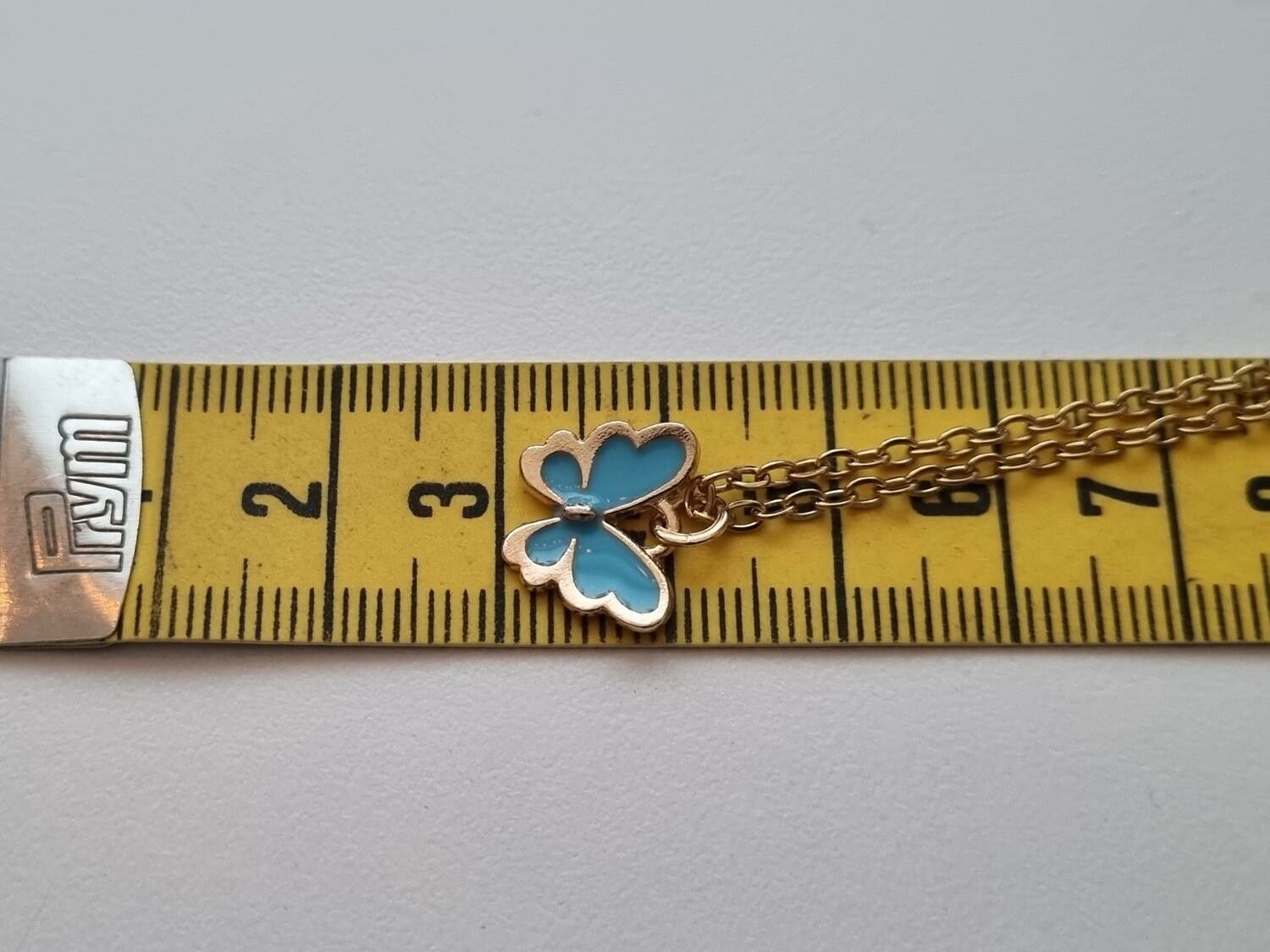 Guldfärgat halsband med en blå fjäril / fjärilsberlock