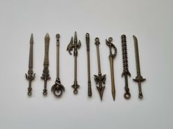 9 st berlocker - Miniatyrvapen, minisvärd, treuddar med mera (bronsfärgade)