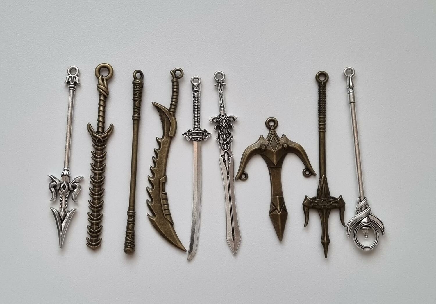 9 st berlocker - Miniatyrvapen, minisvärd, treuddar med mera
