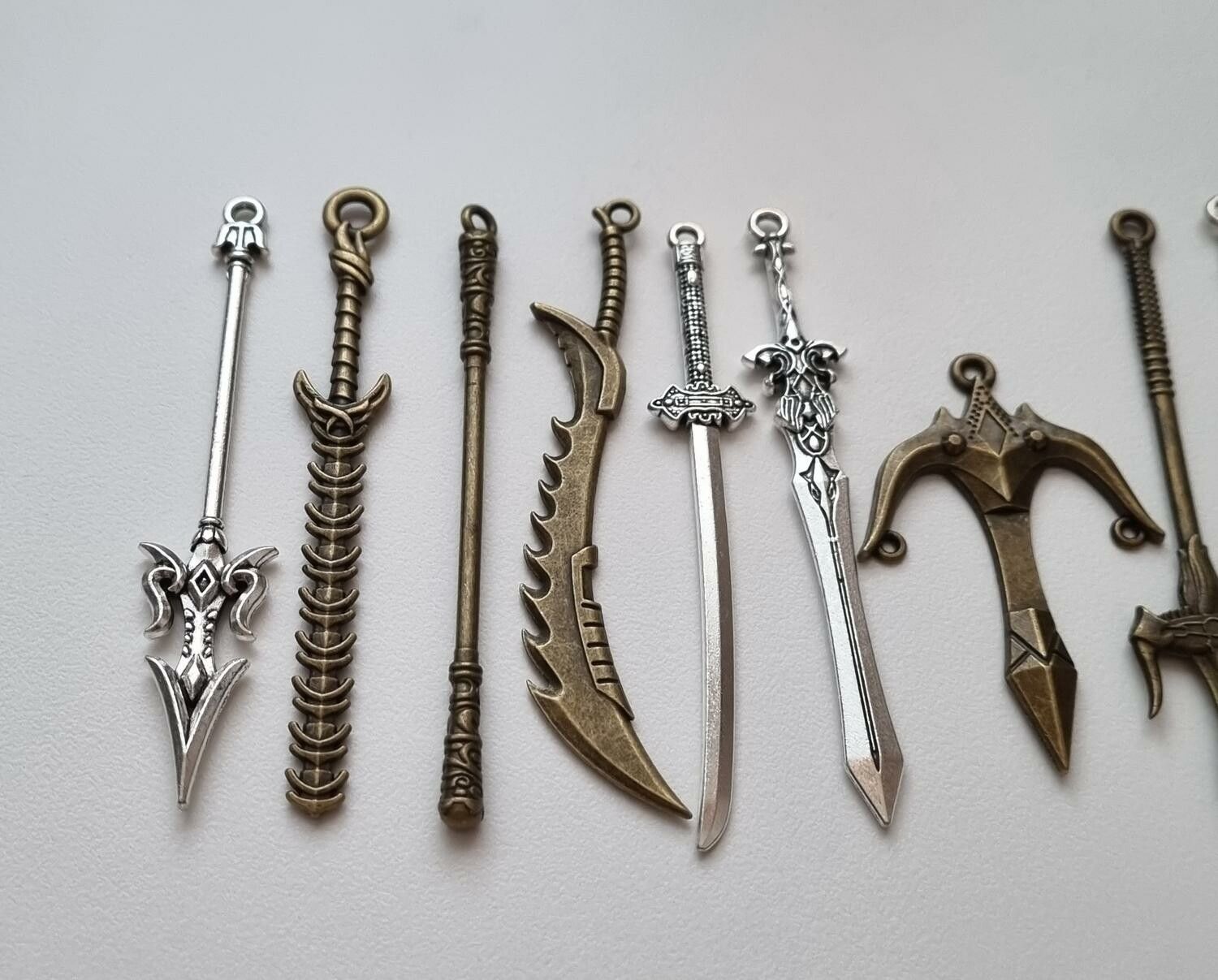 9 st berlocker - Miniatyrvapen, minisvärd, treuddar med mera