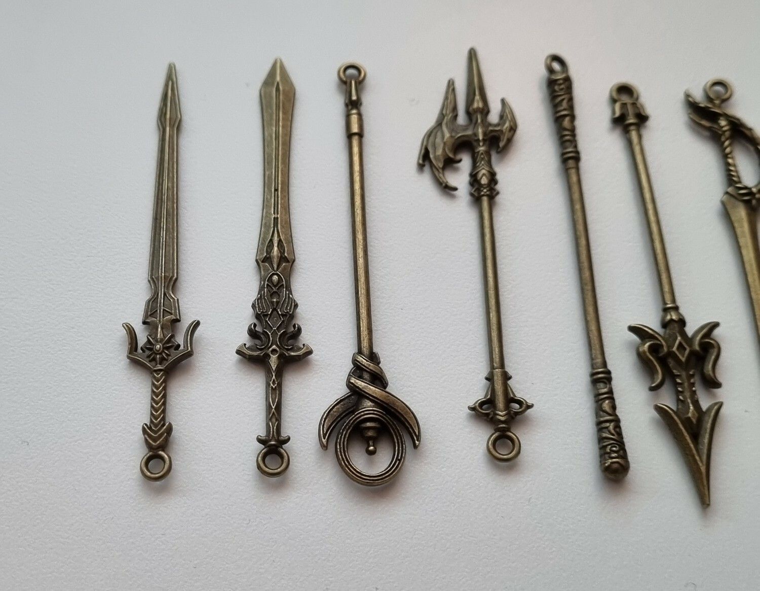 9 st berlocker - Miniatyrvapen, minisvärd, treuddar med mera (bronsfärgade)