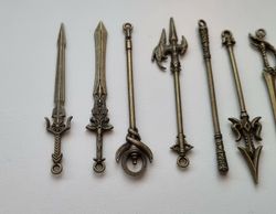 9 st berlocker - Miniatyrvapen, minisvärd, treuddar med mera (bronsfärgade)