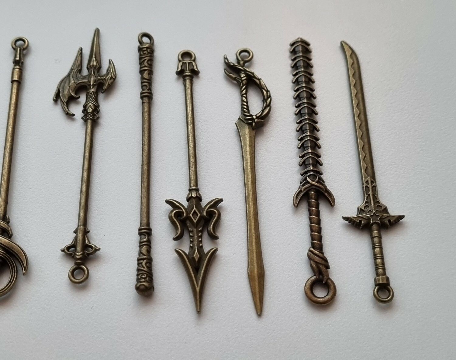 9 st berlocker - Miniatyrvapen, minisvärd, treuddar med mera (bronsfärgade)