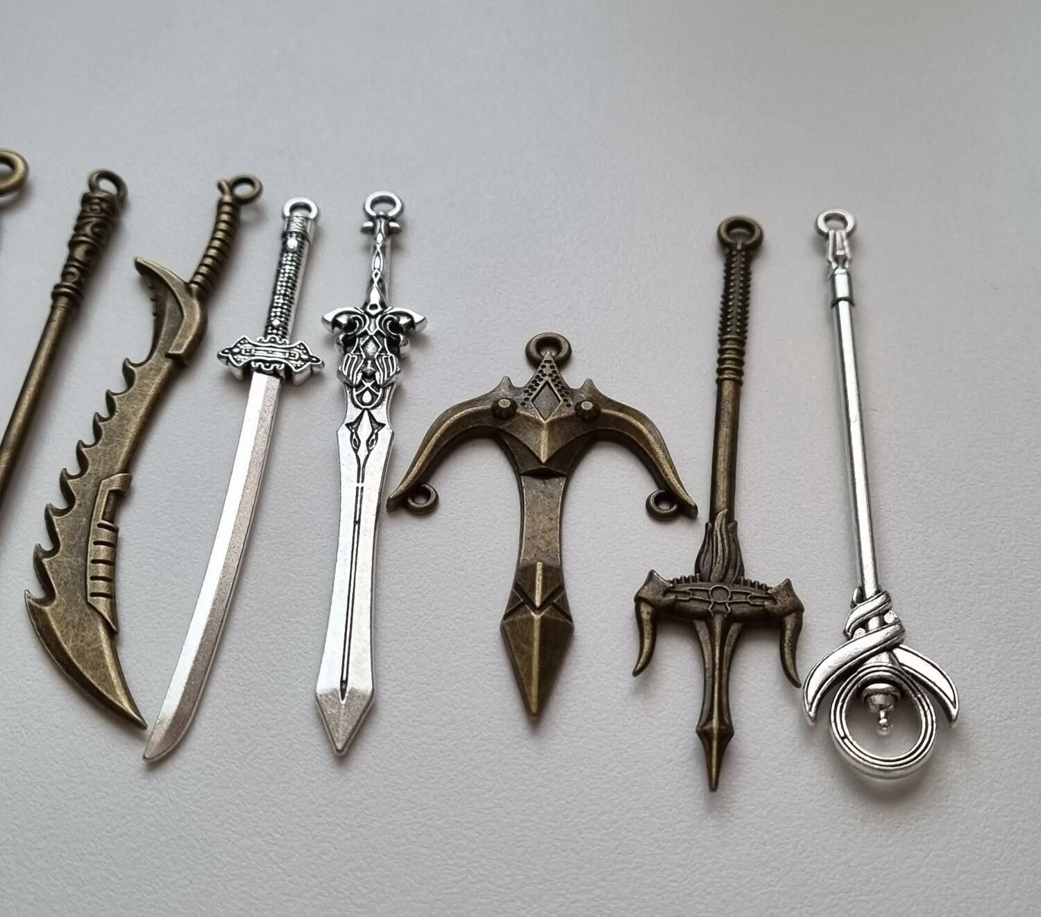 9 st berlocker - Miniatyrvapen, minisvärd, treuddar med mera