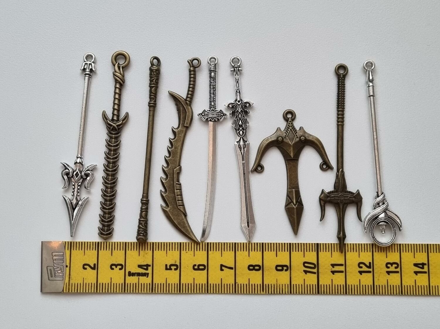 9 st berlocker - Miniatyrvapen, minisvärd, treuddar med mera