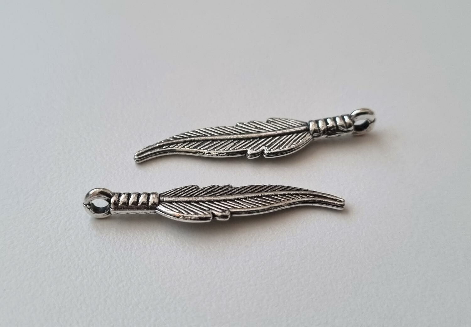 2 st silverfärgade fjädrar / berlocker / hängen