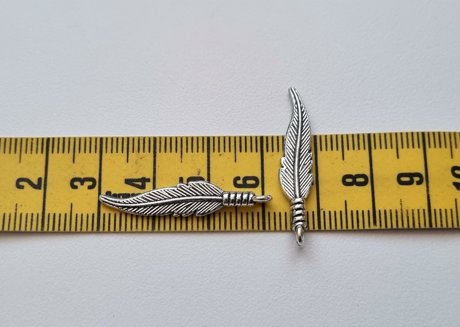 2 st silverfärgade fjädrar / berlocker / hängen