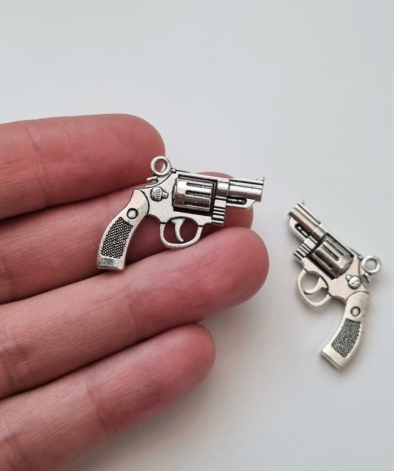 2 st silverfärgade revolvrar / pistoler. Hängen / berlocker