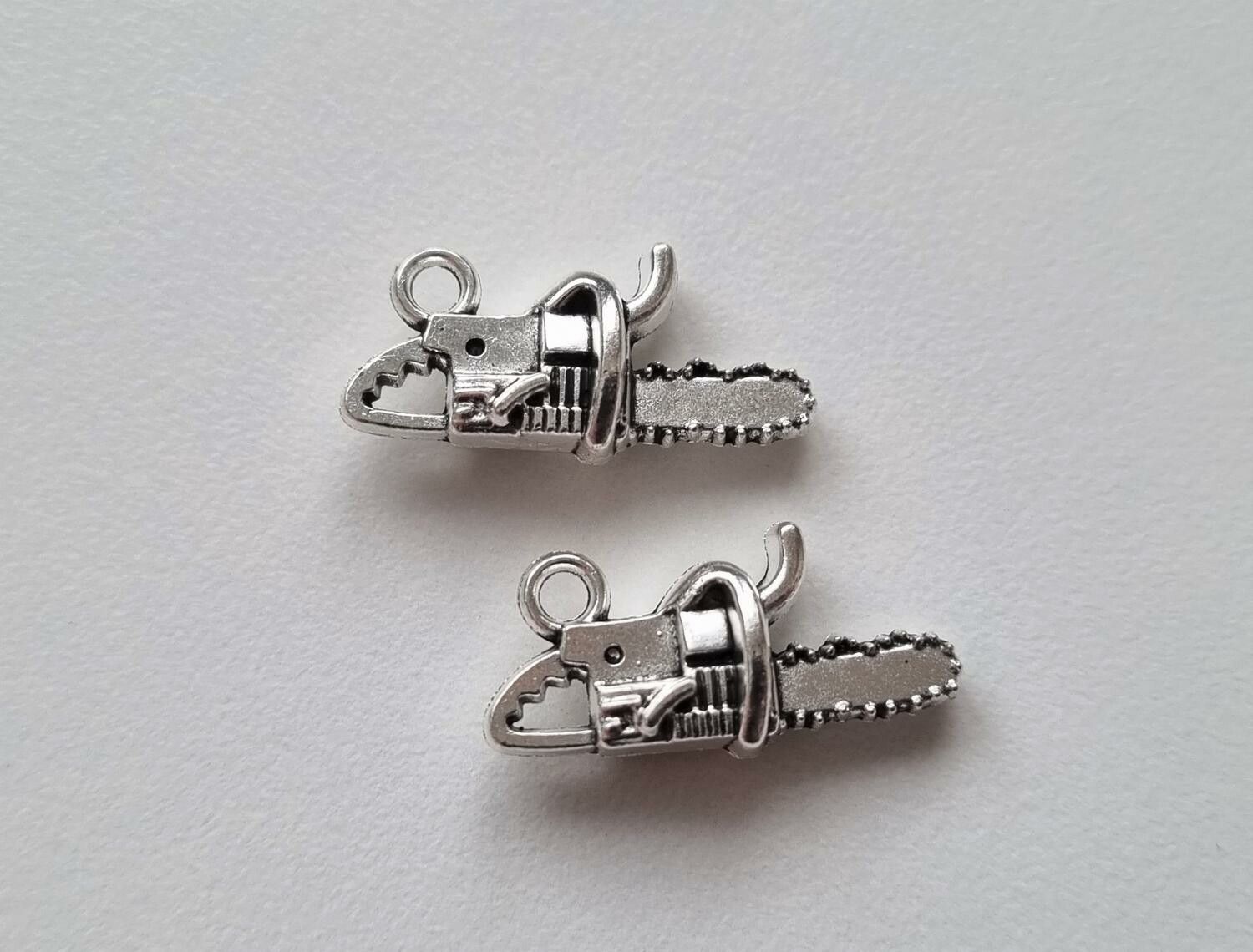 2 st silverfärgade motorsågar, hängen / berlocker