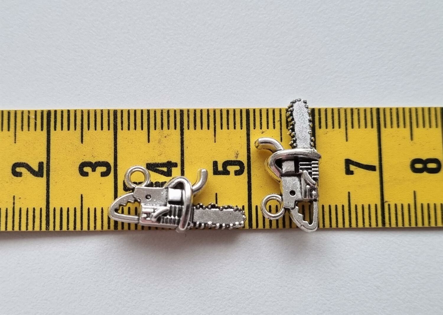 2 st silverfärgade motorsågar, hängen / berlocker