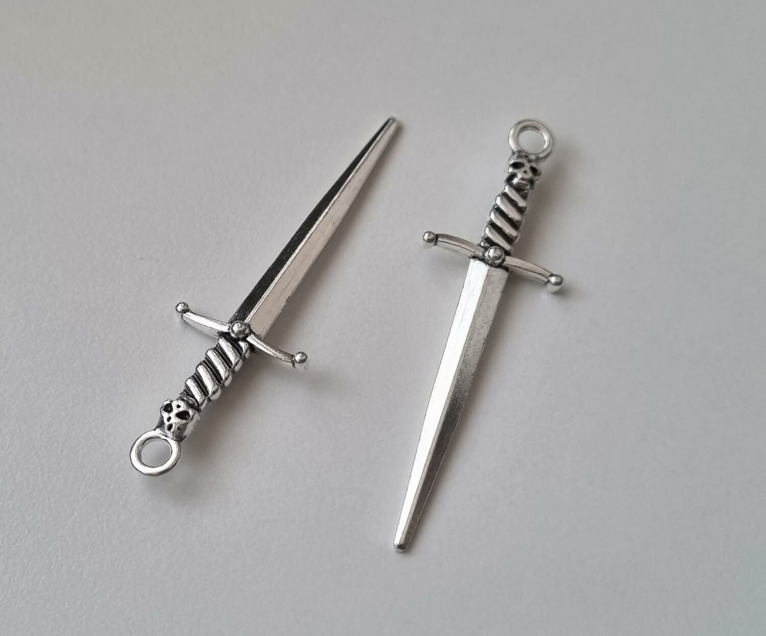 2 st silverfärgade svärd med dödskalle. Berlocker / hänge / charm