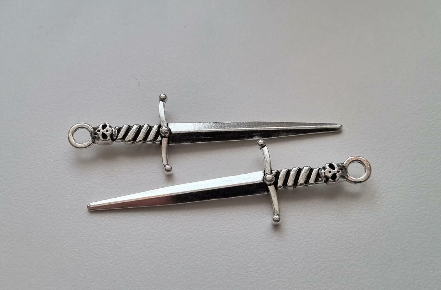 2 st silverfärgade svärd med dödskalle. Berlocker / hänge / charm