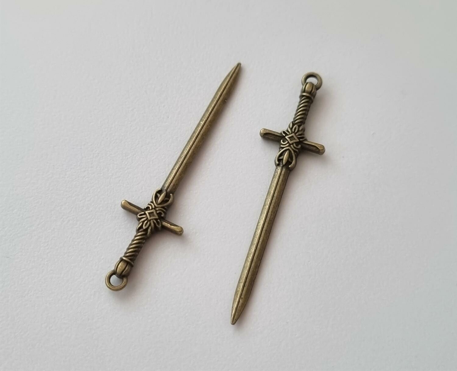 2 st bronsfärgade svärd. Berlocker / hänge / charm