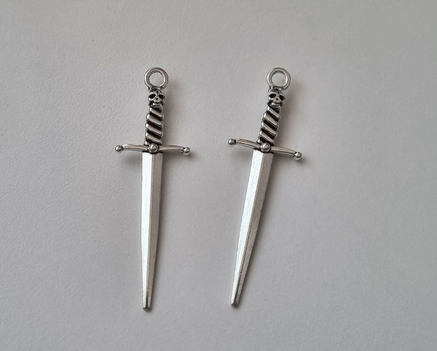 2 st silverfärgade svärd med dödskalle. Berlocker / hänge / charm