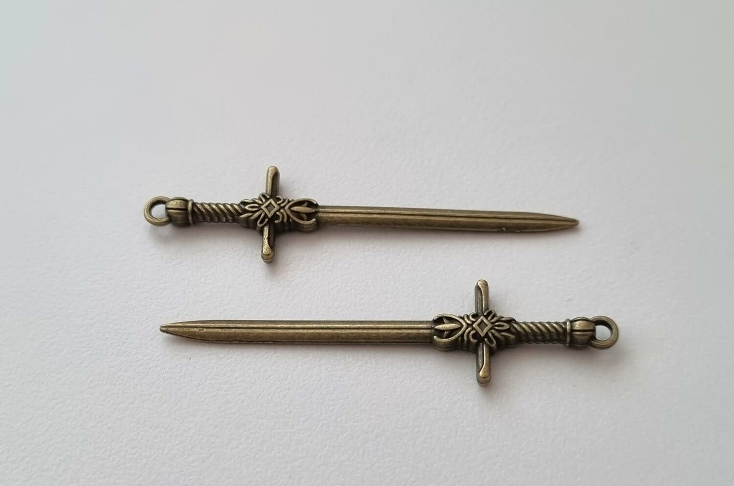 2 st bronsfärgade svärd. Berlocker / hänge / charm