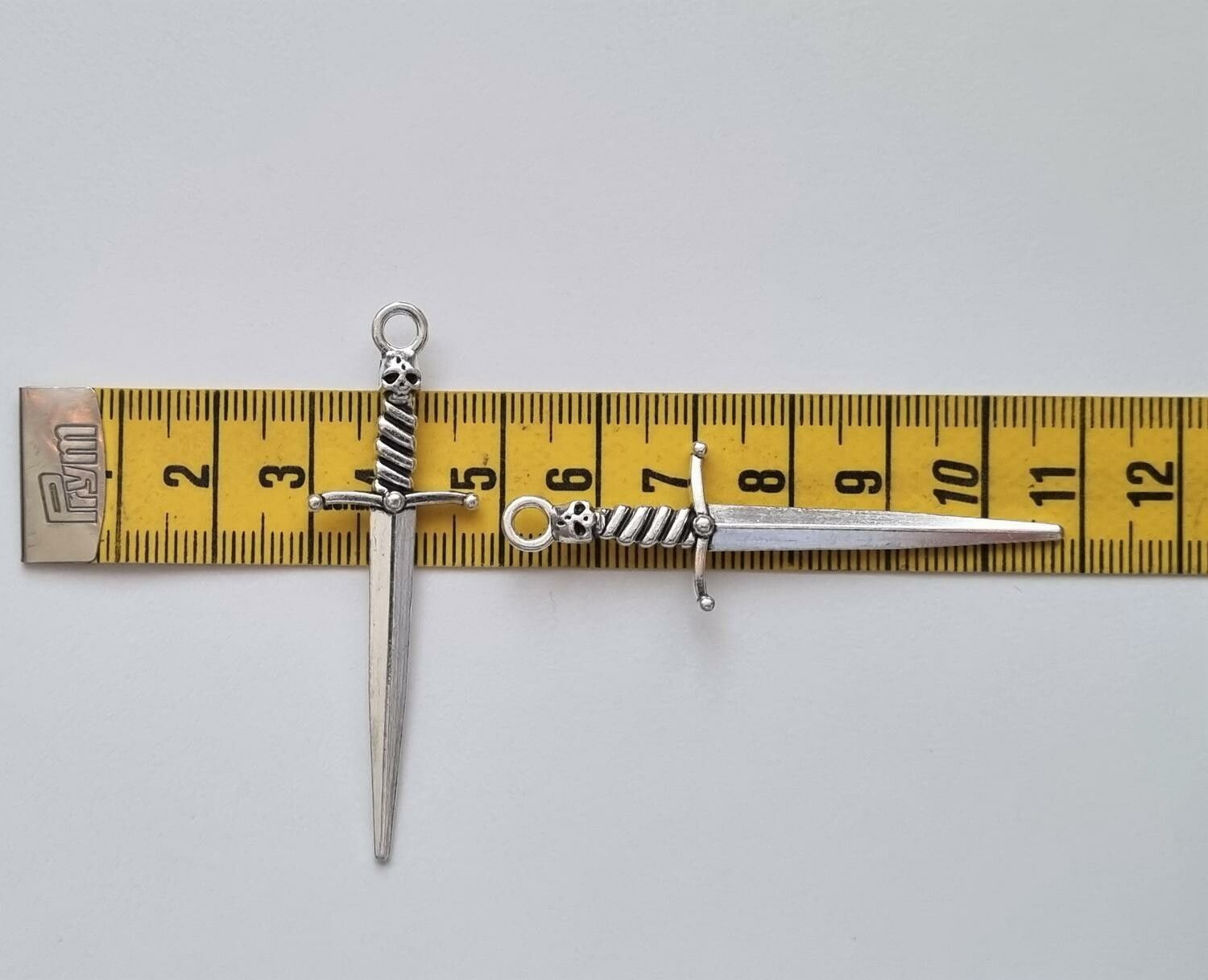 2 st silverfärgade svärd med dödskalle. Berlocker / hänge / charm
