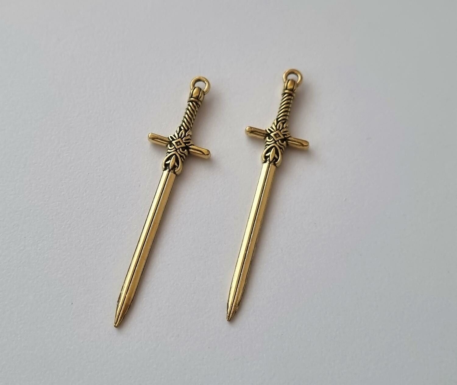 2 st guldfärgade svärd. Berlocker / hänge / charm