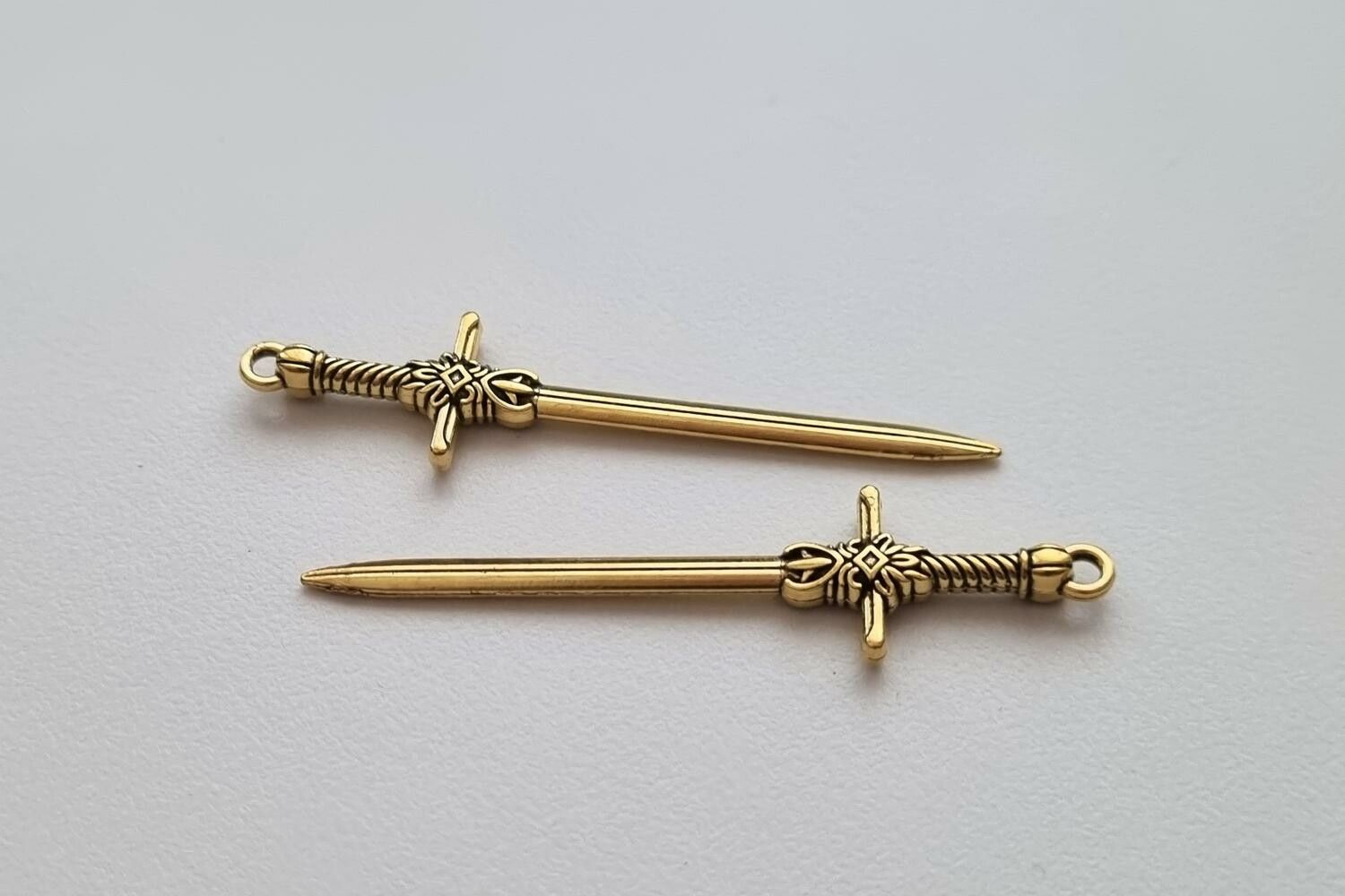 2 st guldfärgade svärd. Berlocker / hänge / charm