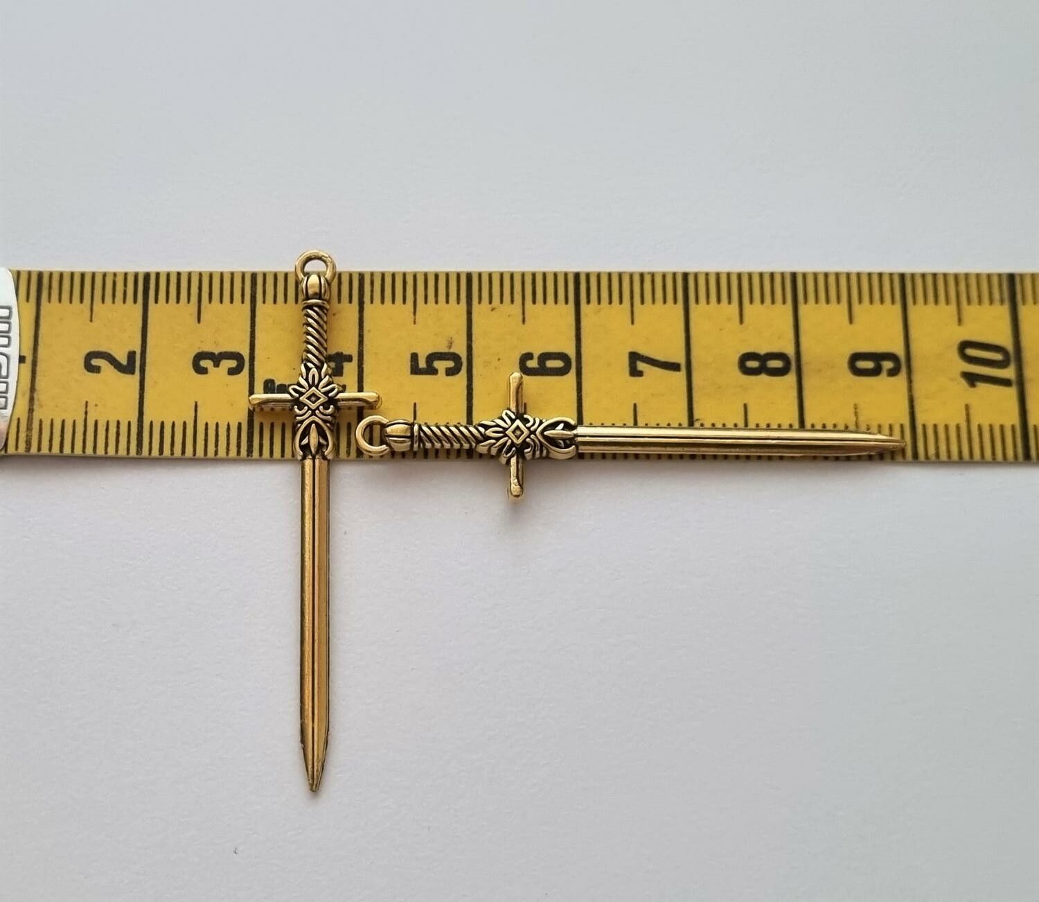 2 st guldfärgade svärd. Berlocker / hänge / charm