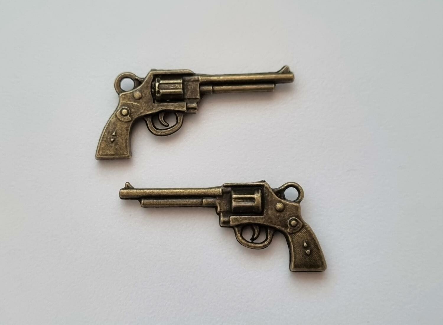 2 st bronsfärgade revolvrar / pistoler. Berlocker / charms / miniatyrer