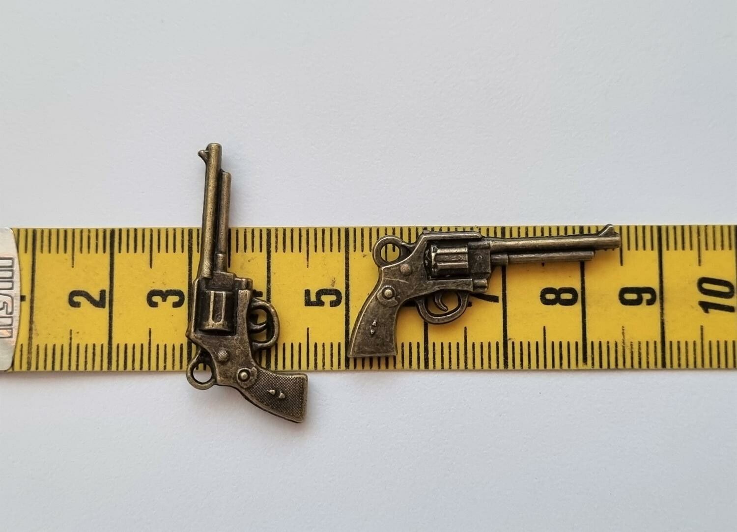2 st bronsfärgade revolvrar / pistoler. Berlocker / charms / miniatyrer