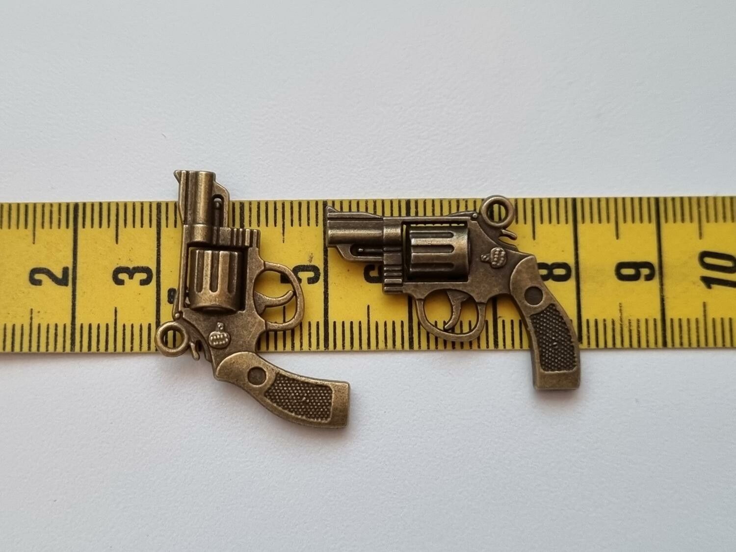 2 st bronsfärgade revolvrar / pistoler. Hängen / berlocker