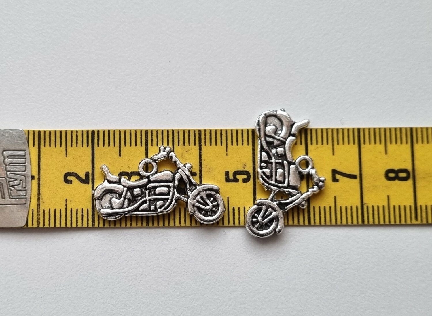 2 st silverfärgade motorcyklar, berlocker