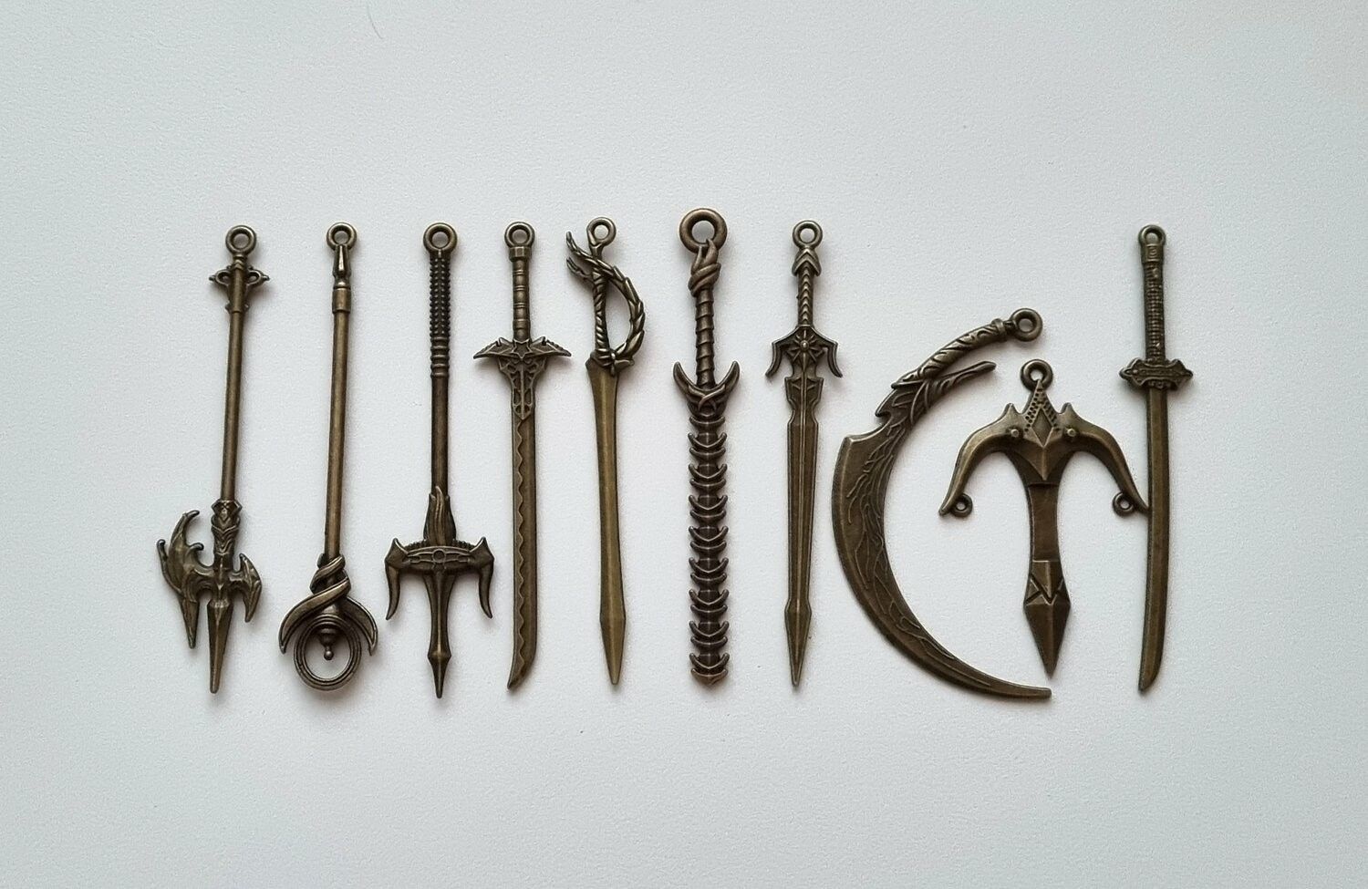 10 st berlocker - Miniatyrvapen, minisvärd, treuddar med mera (bronsfärgade)