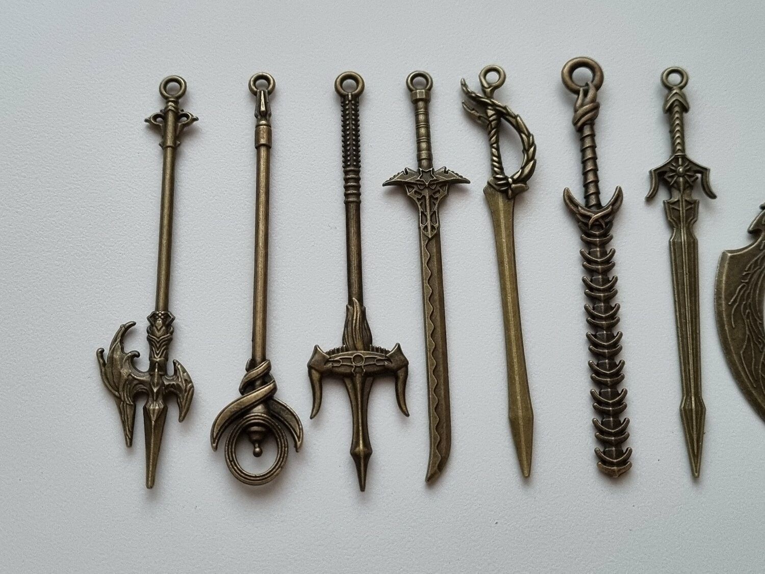 10 st berlocker - Miniatyrvapen, minisvärd, treuddar med mera (bronsfärgade)