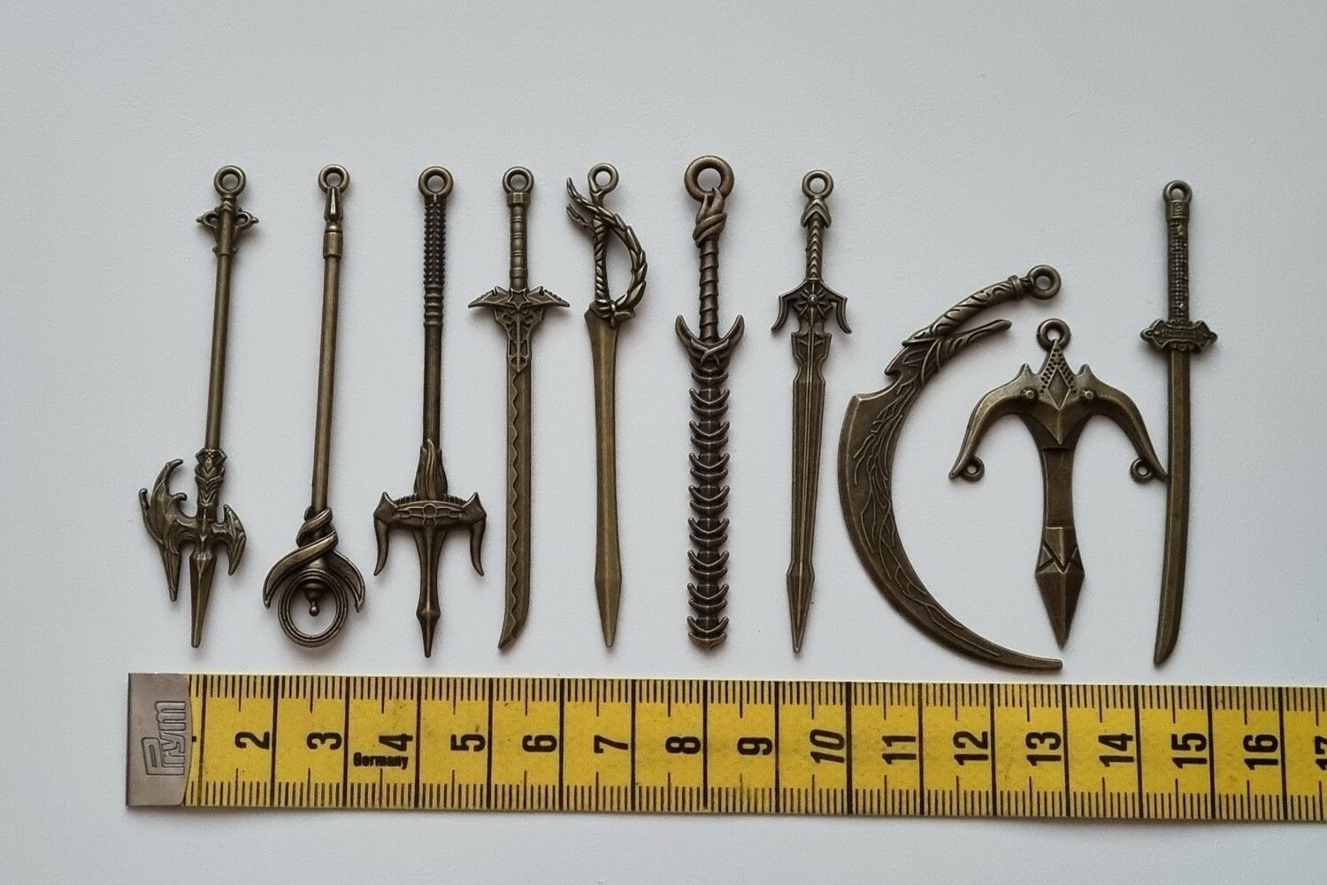 10 st berlocker - Miniatyrvapen, minisvärd, treuddar med mera (bronsfärgade)