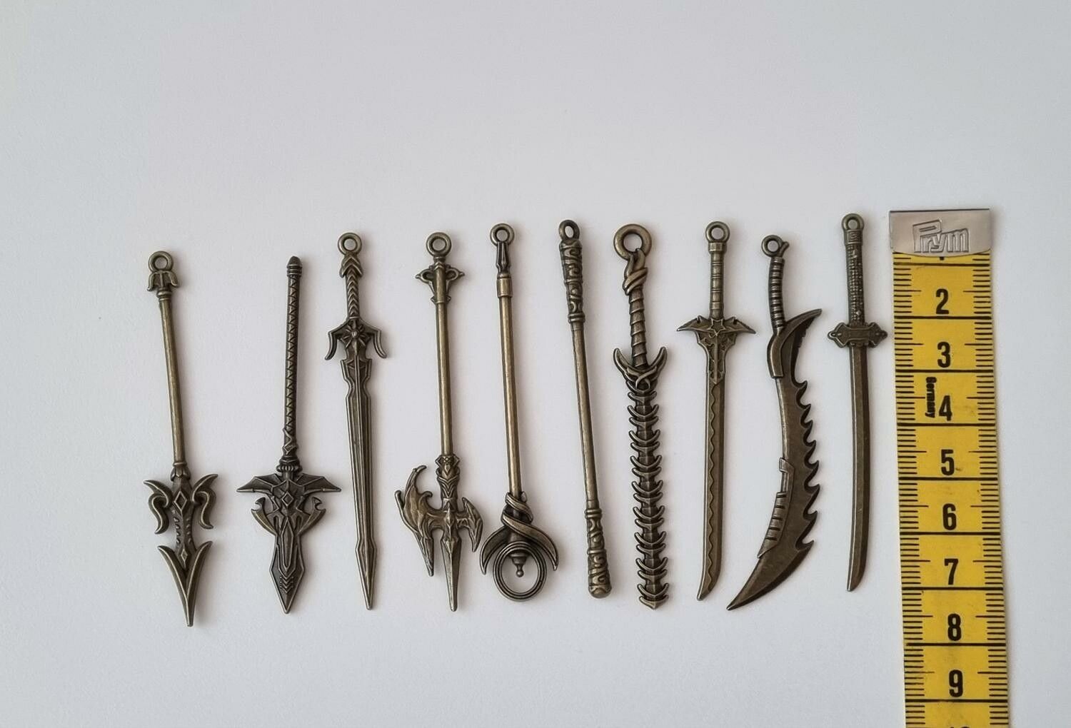 10 st berlocker - Miniatyrvapen, minisvärd, treuddar med mera. Fina miniatyrer