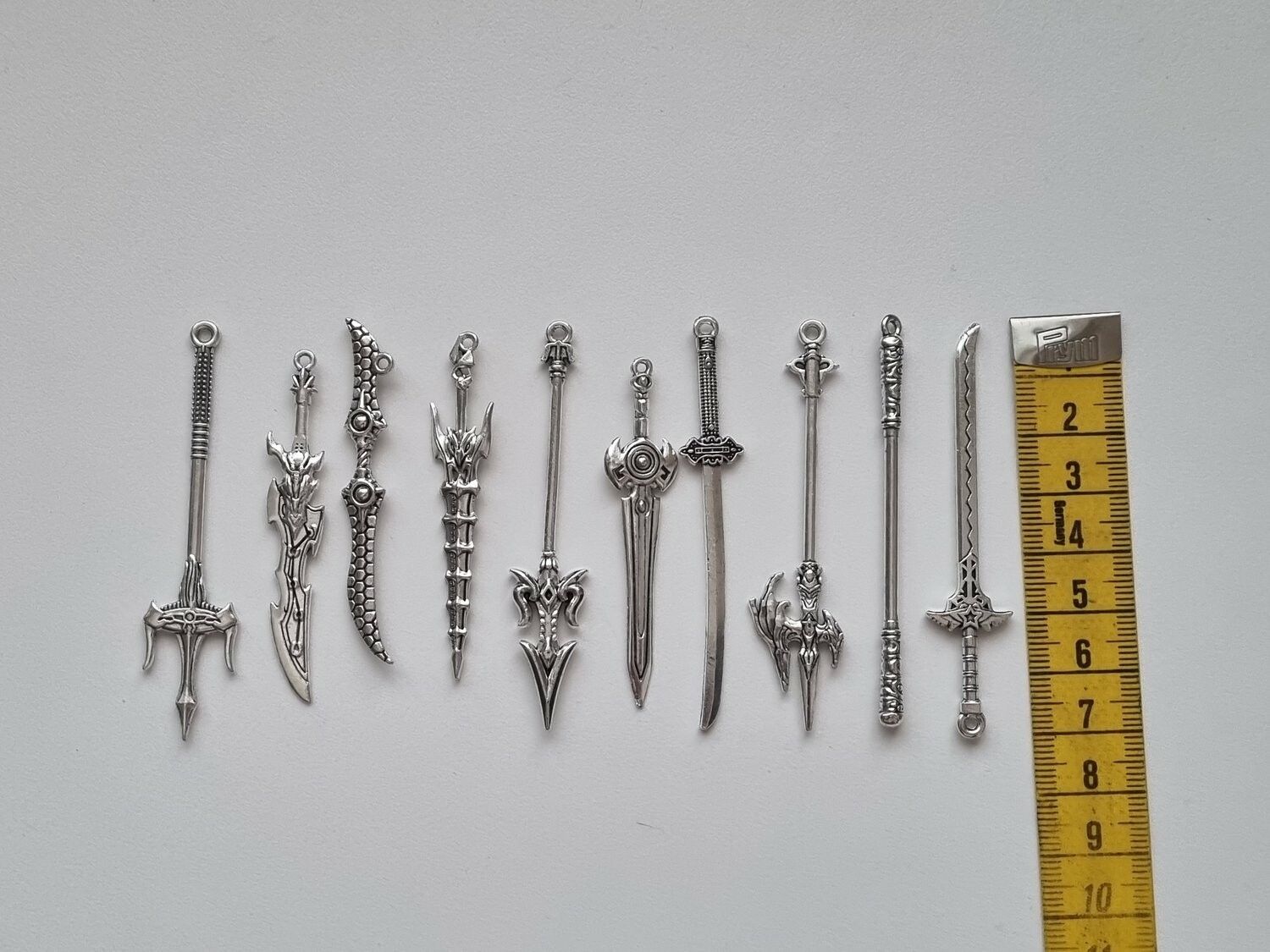 10 st berlocker - Miniatyrvapen, minisvärd, treuddar med mera