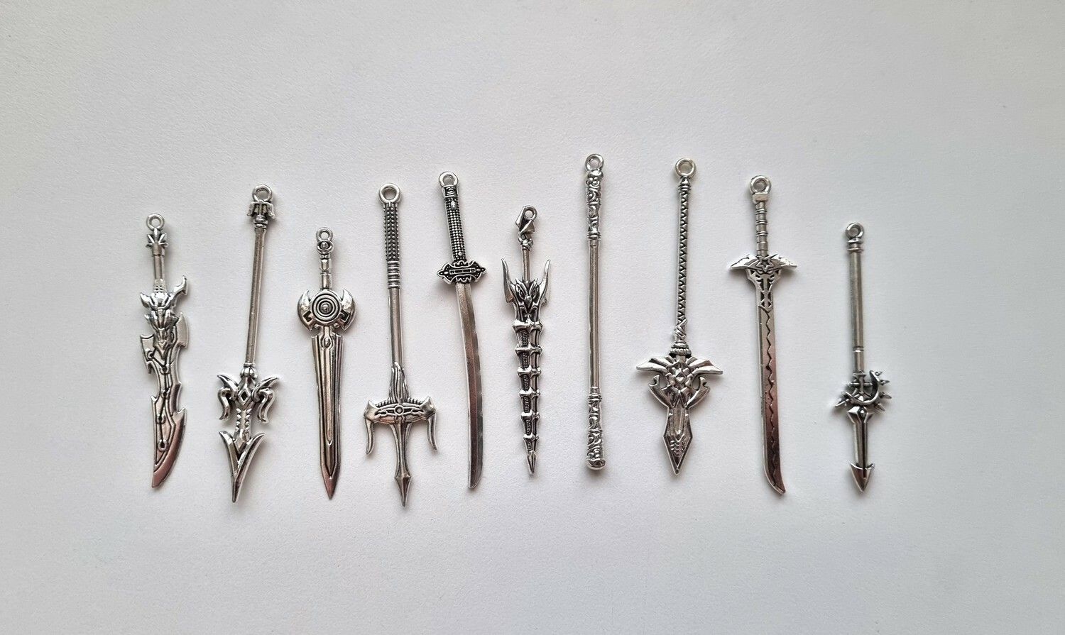 10 st berlocker - Miniatyrvapen, minisvärd, treuddar med mera