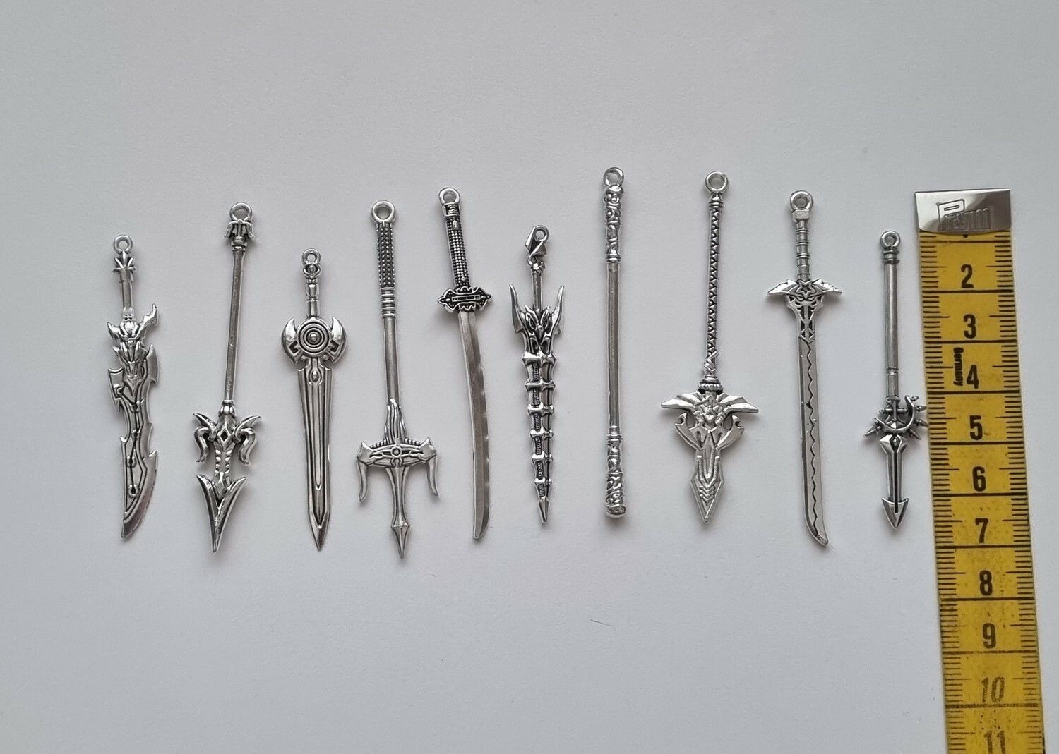 10 st berlocker - Miniatyrvapen, minisvärd, treuddar med mera