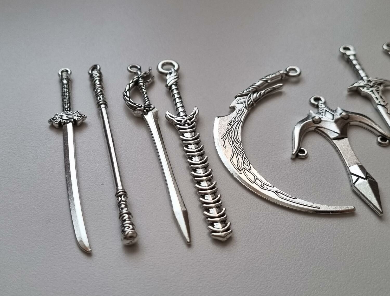 10 st berlocker - Miniatyrvapen, minisvärd, treuddar med mera (silverfärgade)