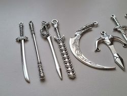 10 st berlocker - Miniatyrvapen, minisvärd, treuddar med mera (silverfärgade)