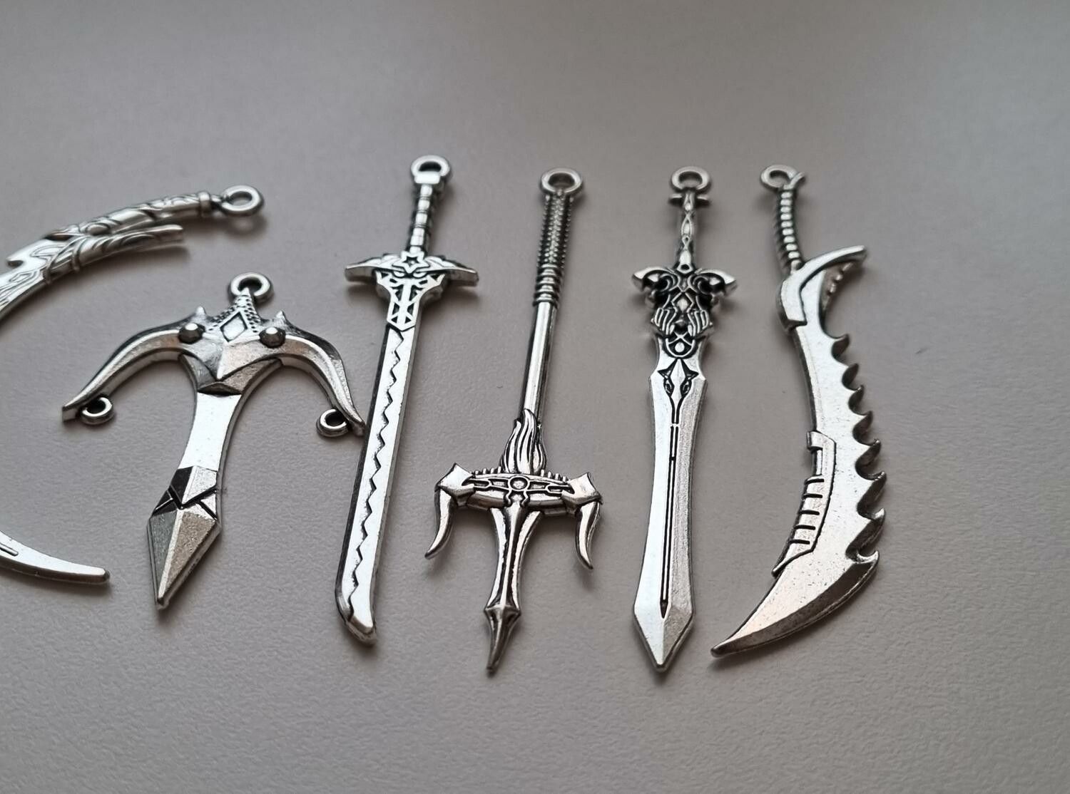 10 st berlocker - Miniatyrvapen, minisvärd, treuddar med mera (silverfärgade)