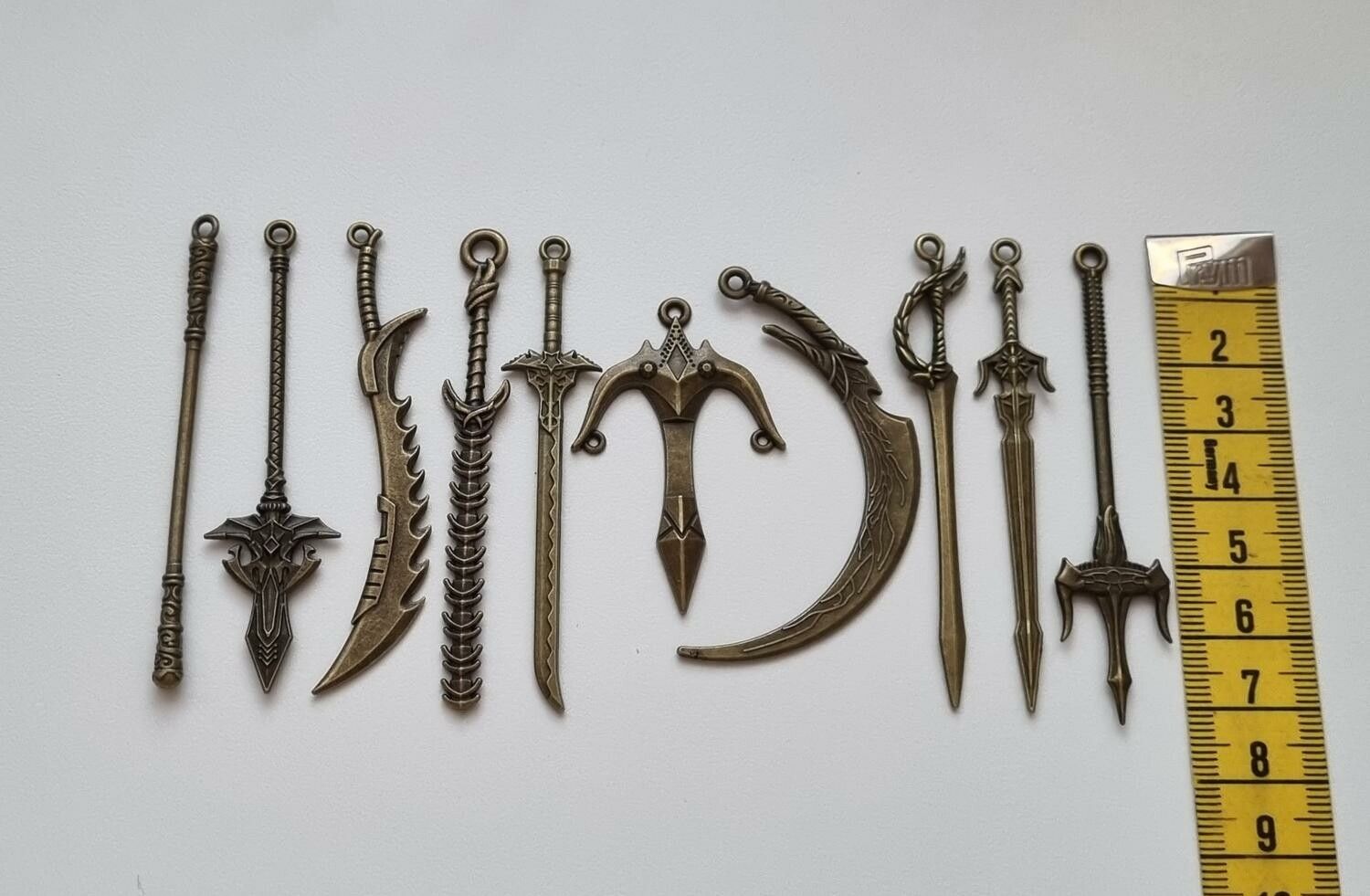 10 st berlocker - Miniatyrvapen, minisvärd, treuddar med mera (bronsfärgde)