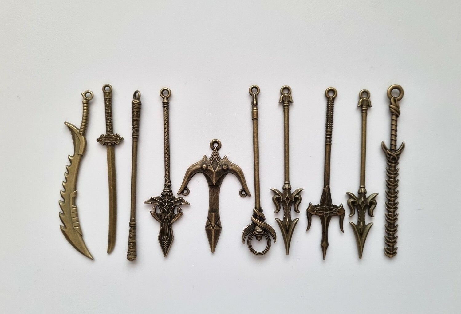 10 st berlocker - Miniatyrvapen, minisvärd, treuddar med mera (bronsfärgade)