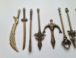 10 st berlocker - Miniatyrvapen, minisvärd, treuddar med mera (bronsfärgade)
