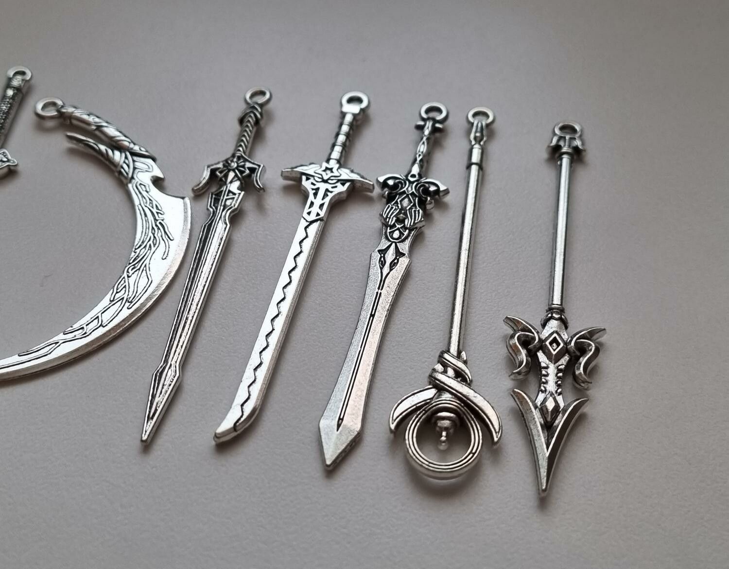 10 st berlocker - Miniatyrvapen, minisvärd, treuddar med mera (silverfärgade)