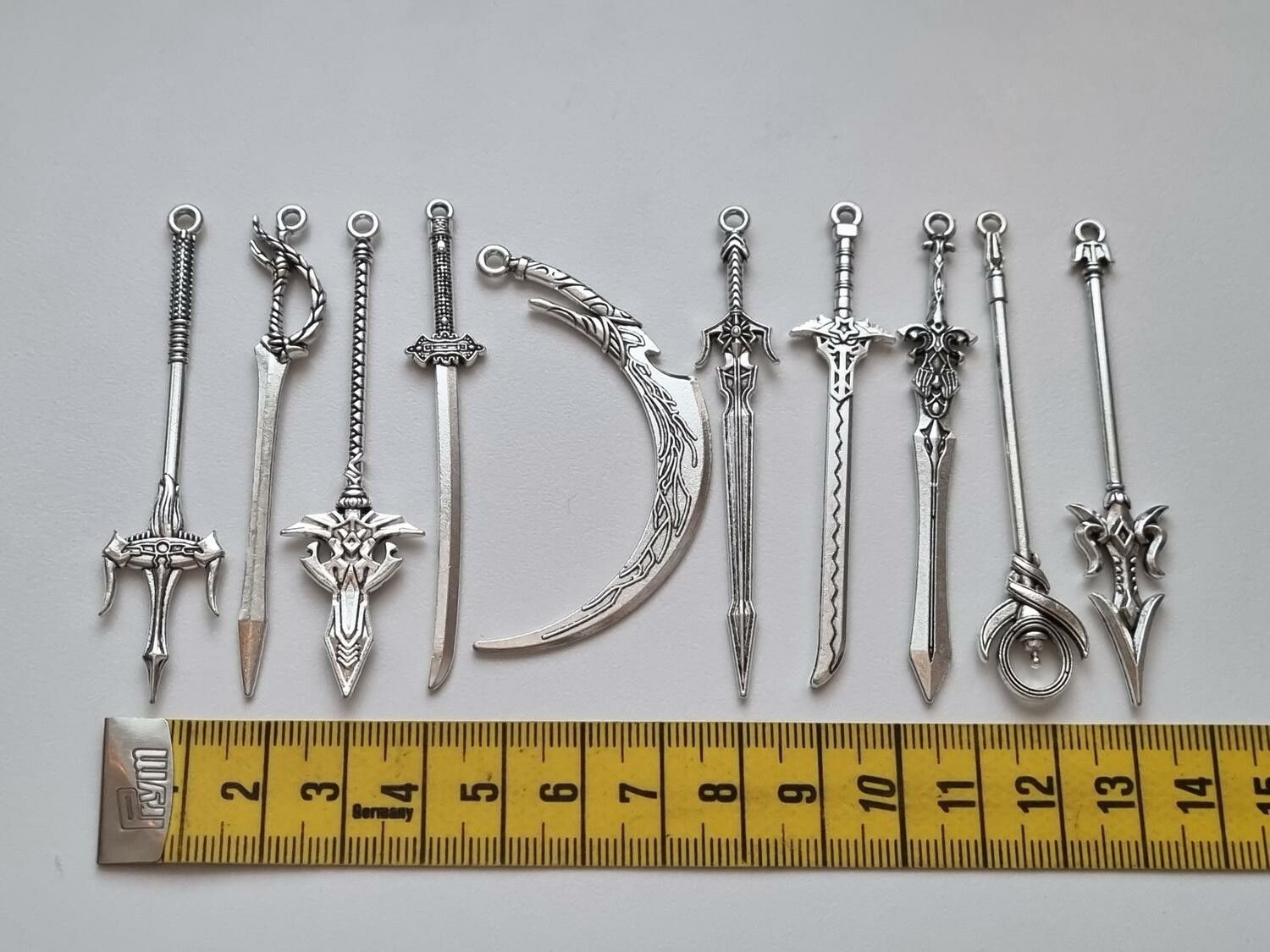 10 st berlocker - Miniatyrvapen, minisvärd, treuddar med mera (silverfärgade)