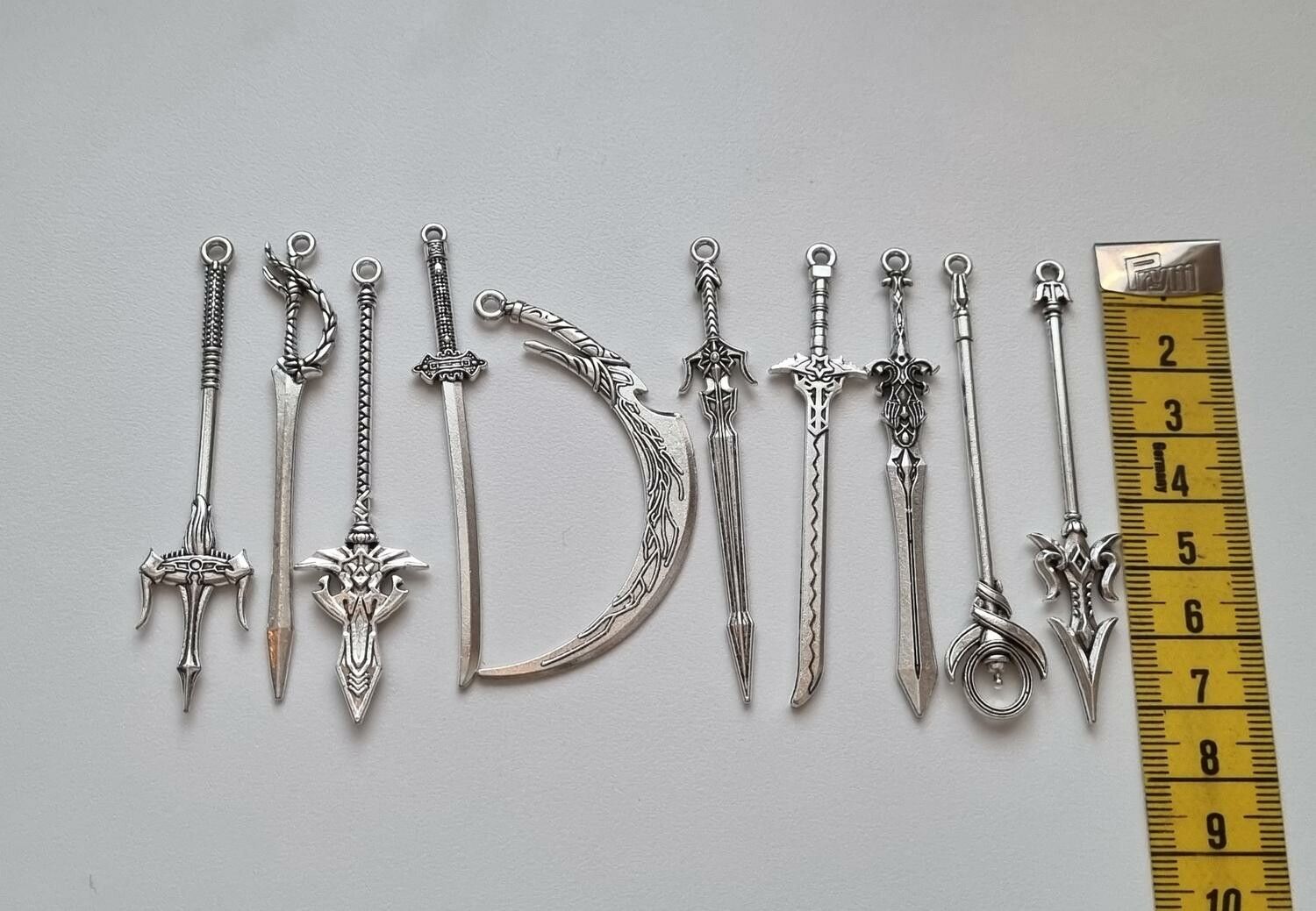 10 st berlocker - Miniatyrvapen, minisvärd, treuddar med mera (silverfärgade)