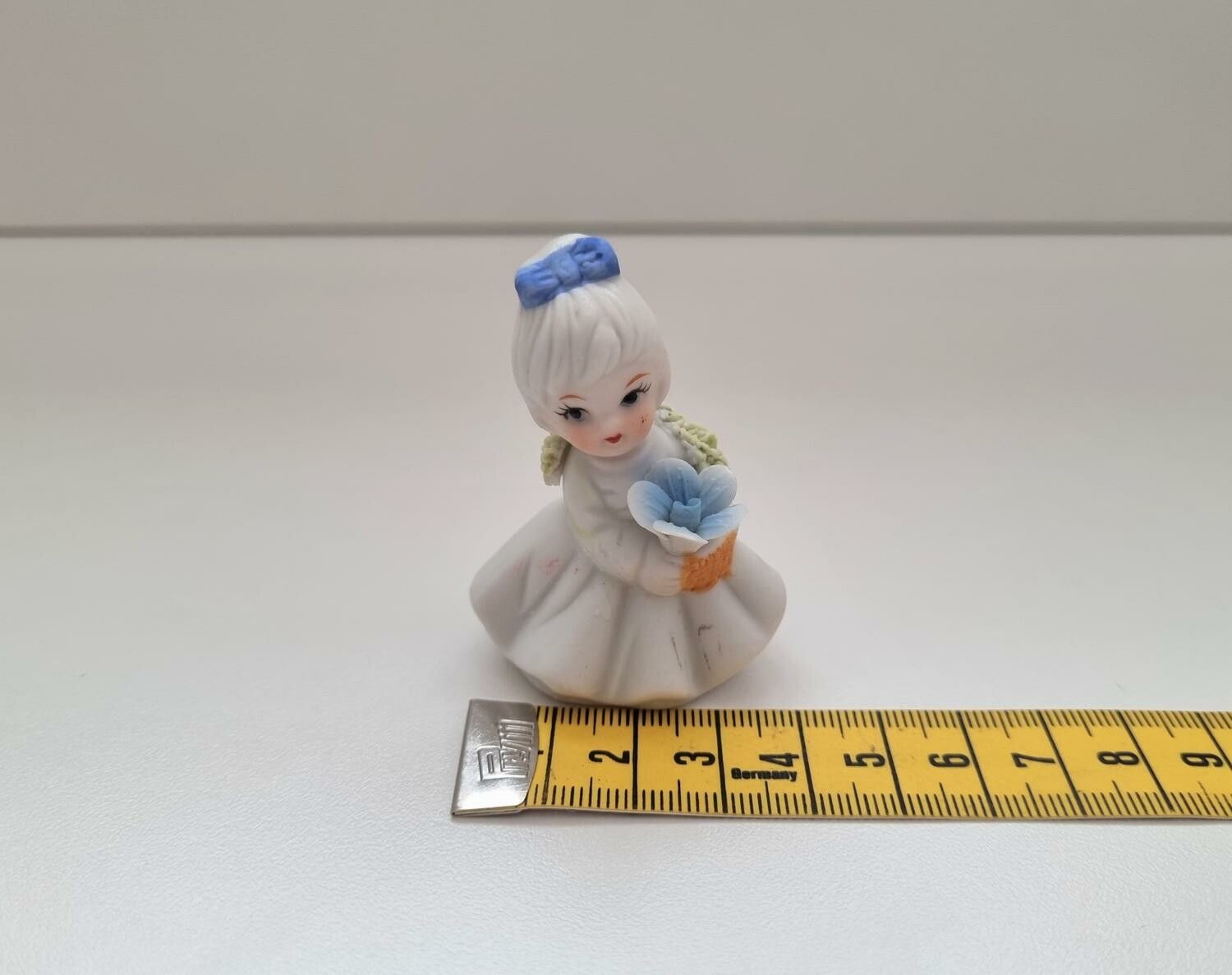 Söt liten figurin, flicka som håller i en blombukett