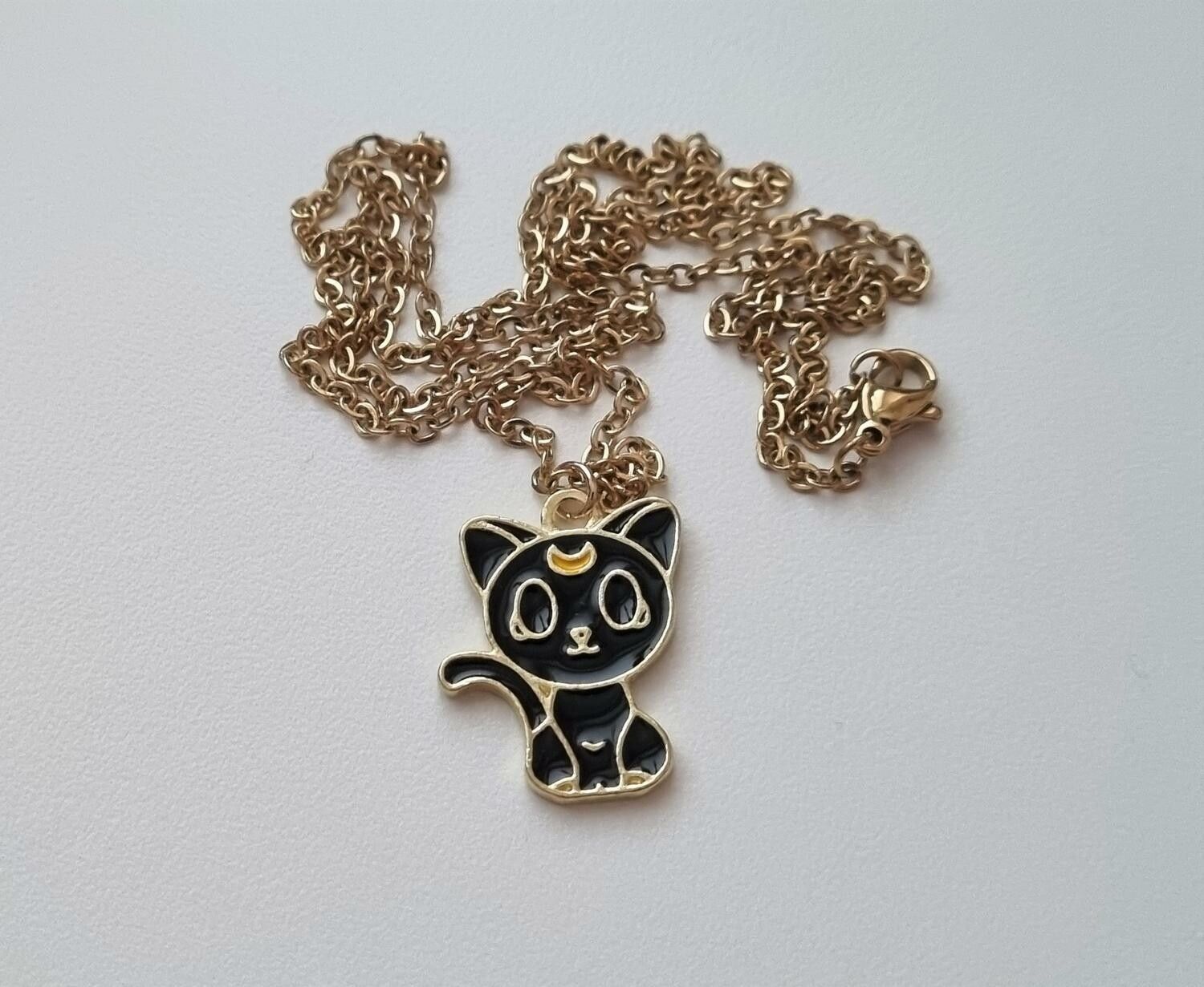 Guldfärgat halsband (60 cm) med en söt liten svart katt som berlock