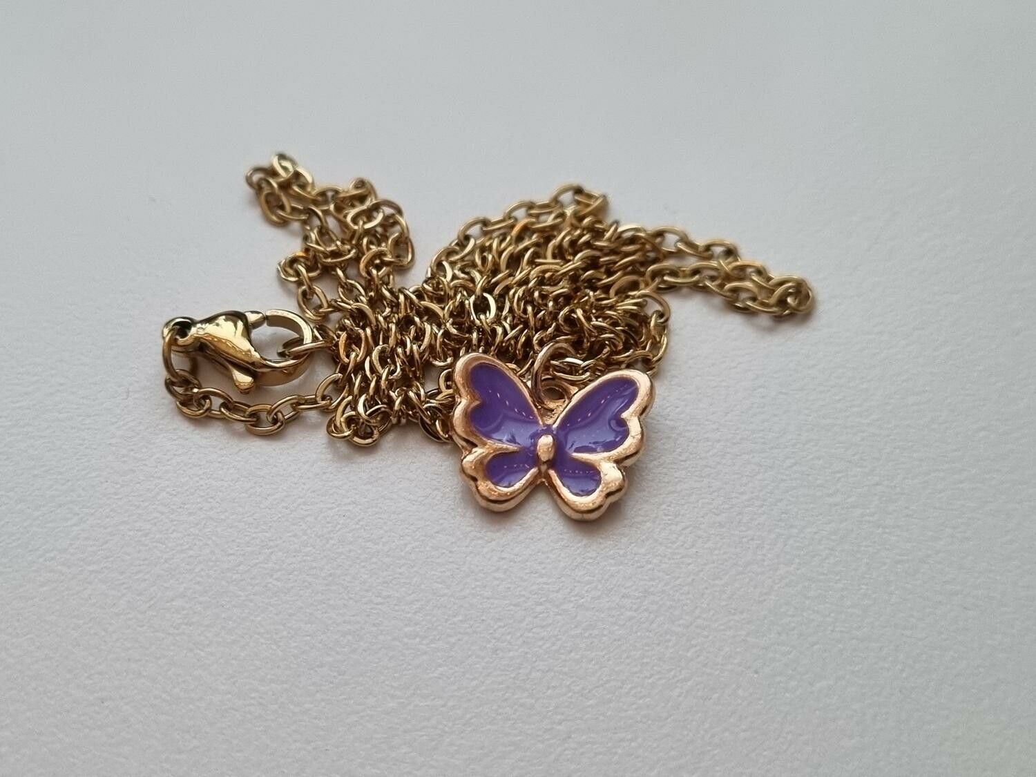 Guldfärgat halsband med en lila fjäril / fjärilsberlock