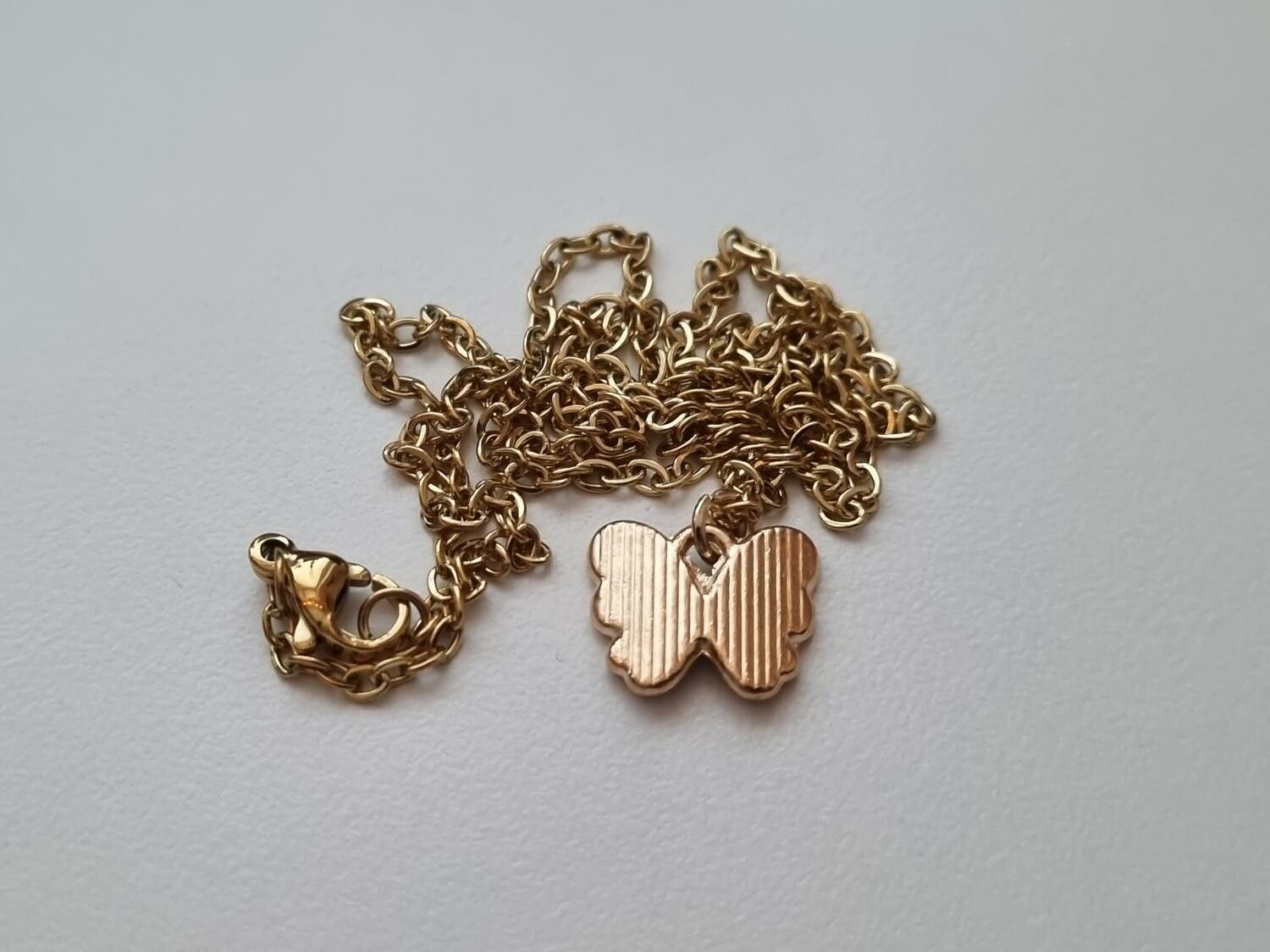 Guldfärgat halsband med en lila fjäril / fjärilsberlock
