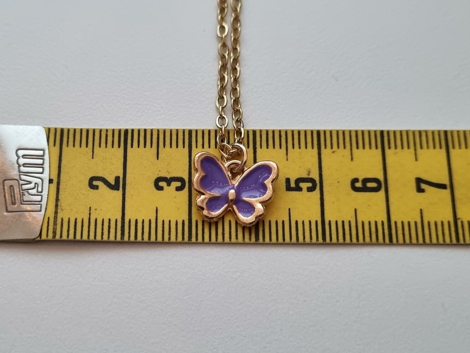 Guldfärgat halsband med en lila fjäril / fjärilsberlock